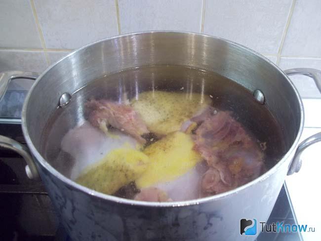 В кастрюлю сложена курица, луковица и продукты залиты водой