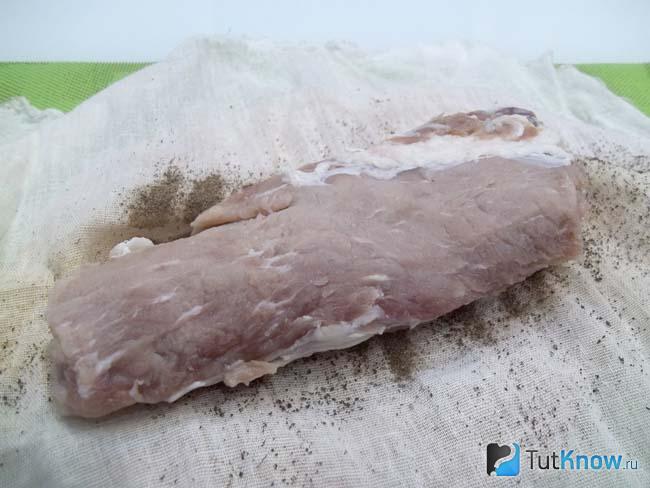 На хлопковую ткань с молотым черным перцем выложено мясо
