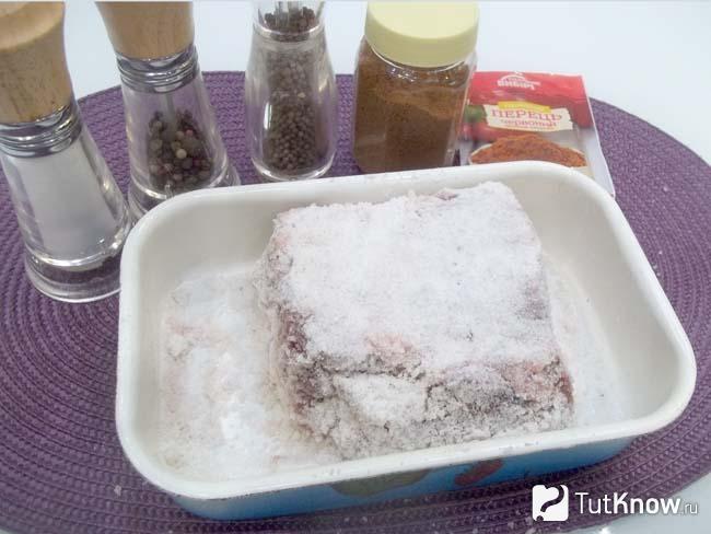 В миску с солью выложено мясо, которое присыпано солью