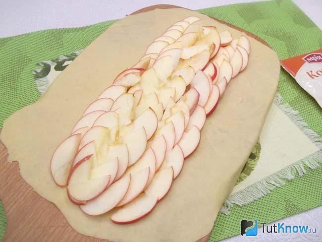 На тесто выложены нарезанные яблоки
