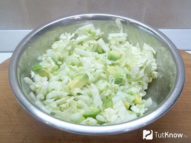 Капуста с авокадо заправлены лимонным соком, маслом и продукты перемешаны
