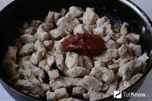 Добавление томатной пасты к мясу на сковороде
