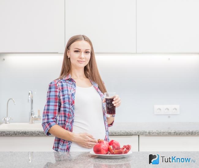 Беременная женщина пьет гранатовый сок