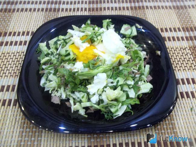 На готовый салат с рукколой, капустой и языком выложено яйцо-пашот