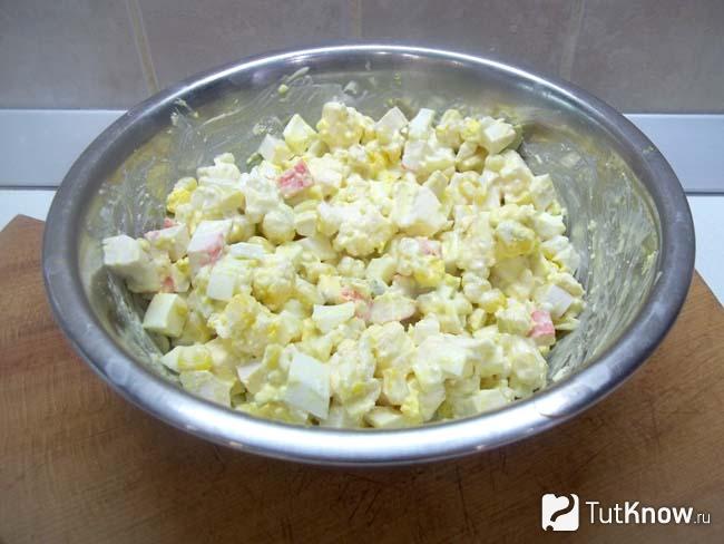 Салат с кукурузой, крабовыми палочками, яйцами и сыром приправлен майонезом