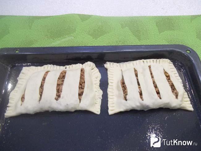 Слойки из покупного теста с мясным фаршем выложены на противень и отправлены в духовку