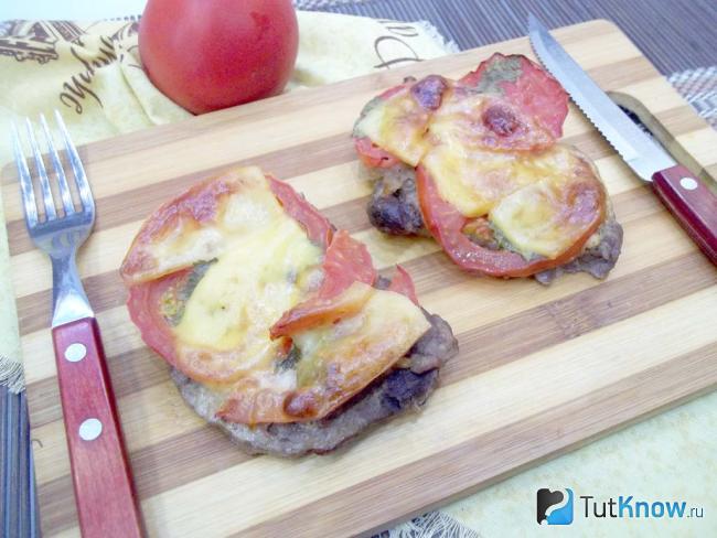 Готовые свиные отбивные с помидорами и сыром в духовке
