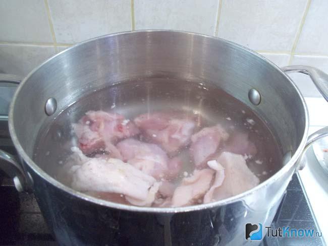 Куриные бедрышки сложены в кастрюлю и залиты водой