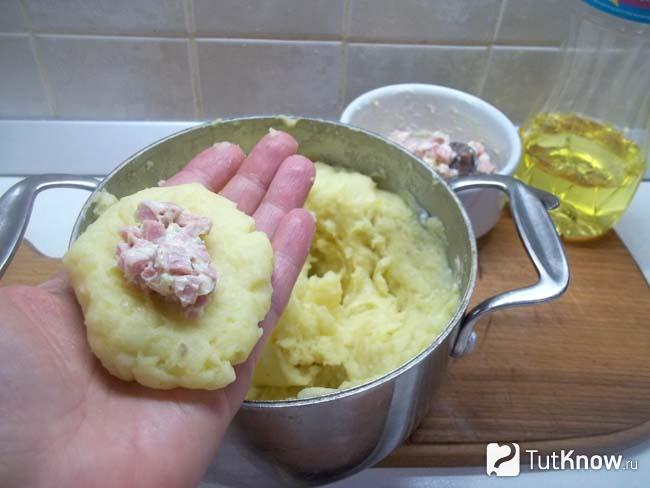 На картофельную лепешку выложена начинка из колбасы