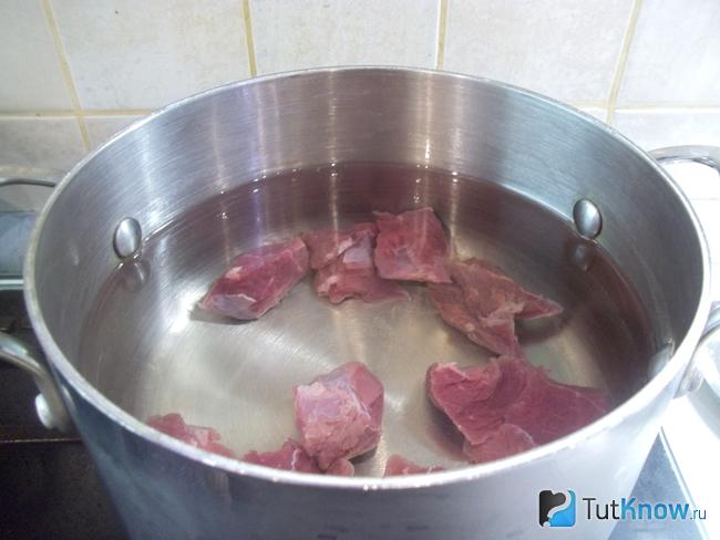 Мясо сложено в кастрюлю и залито водой