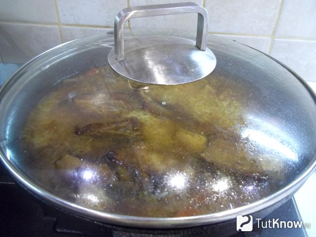 Плов с телячьими ребрышками тушится в сковороде