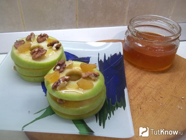 На яблоки выложены изюм, орехи и смазаны медом