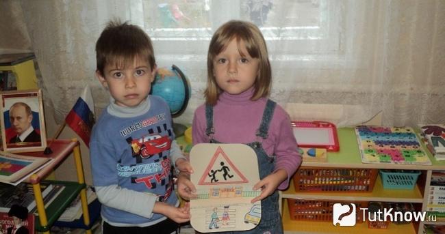 Мальчик и девочка демонстрируют рисунок дорожного знака