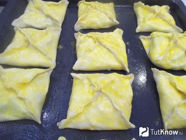 Конвертики из слоено-дрожжевого теста с колбасой, сыром и кетчупом выложены на противень