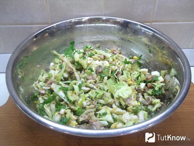 Готовый салат с капустой, яйцами, огурцами и консервированной сайрой