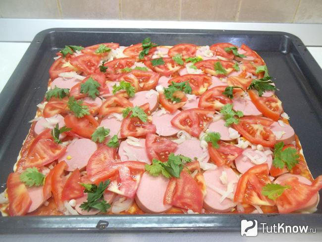 На тесто выложены листья кинзы