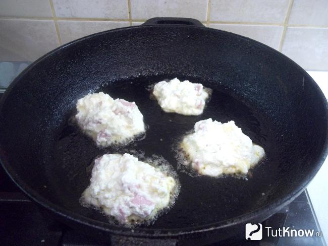 Творожные сырники с сыром и колбасой жарятся на сковороде