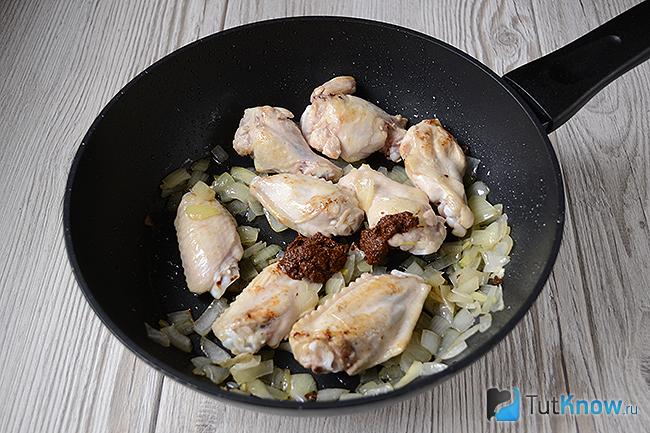 Куриные крылышки с луком и специями на сковороде