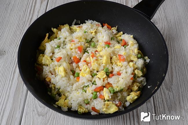 Готовый рис с овощами и яйцом на сковороде