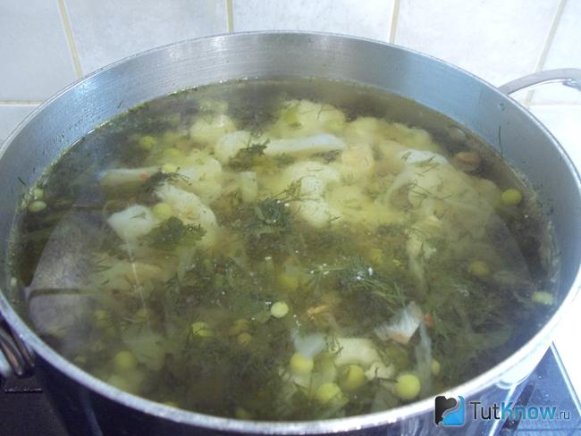 Готовый куриный суп с молодым зеленым горошком и капустой