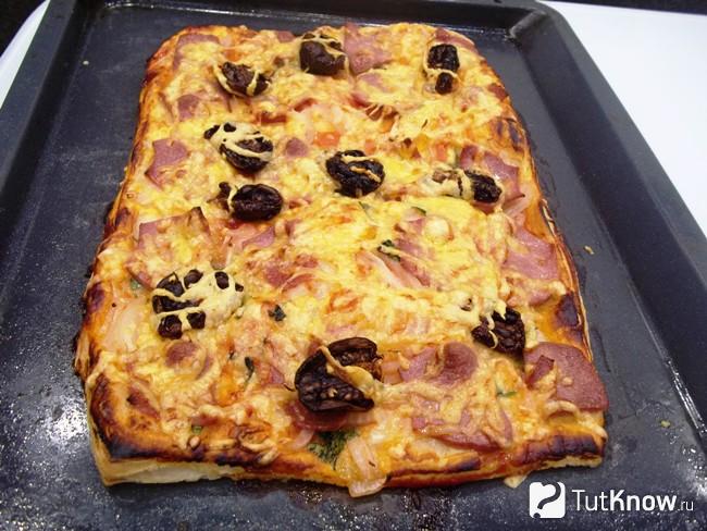 Готовая пицца из слоеного теста с колбасой, сыром и вялеными помидорами