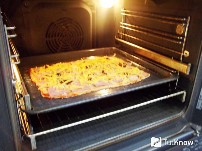 Пицца присыпана сырном и отправлена в духовку