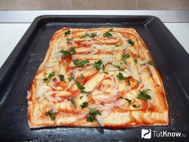 На тесто выложена зелень и репчатый лук