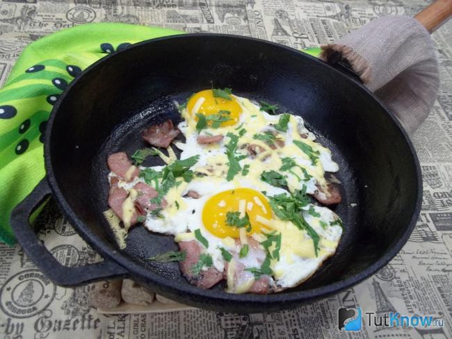 Готовая яичница глазунья с колбасой, сыром и зеленью