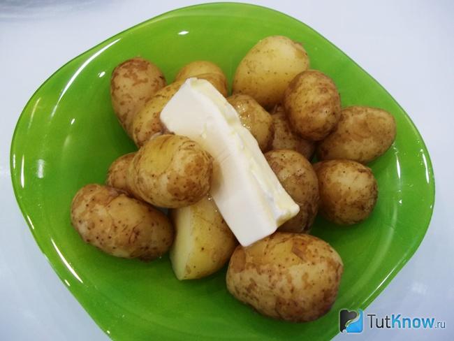 Отваренная картошка разложена по тарелкам и добавлено масло