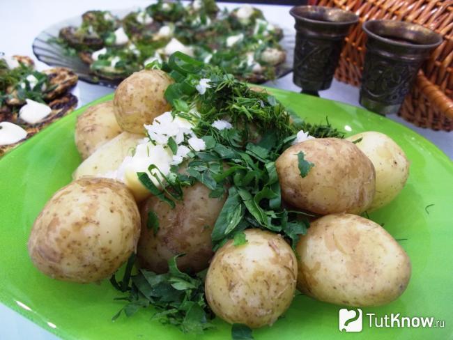 Готовый вареный молодой картофель с чесноком и зеленью